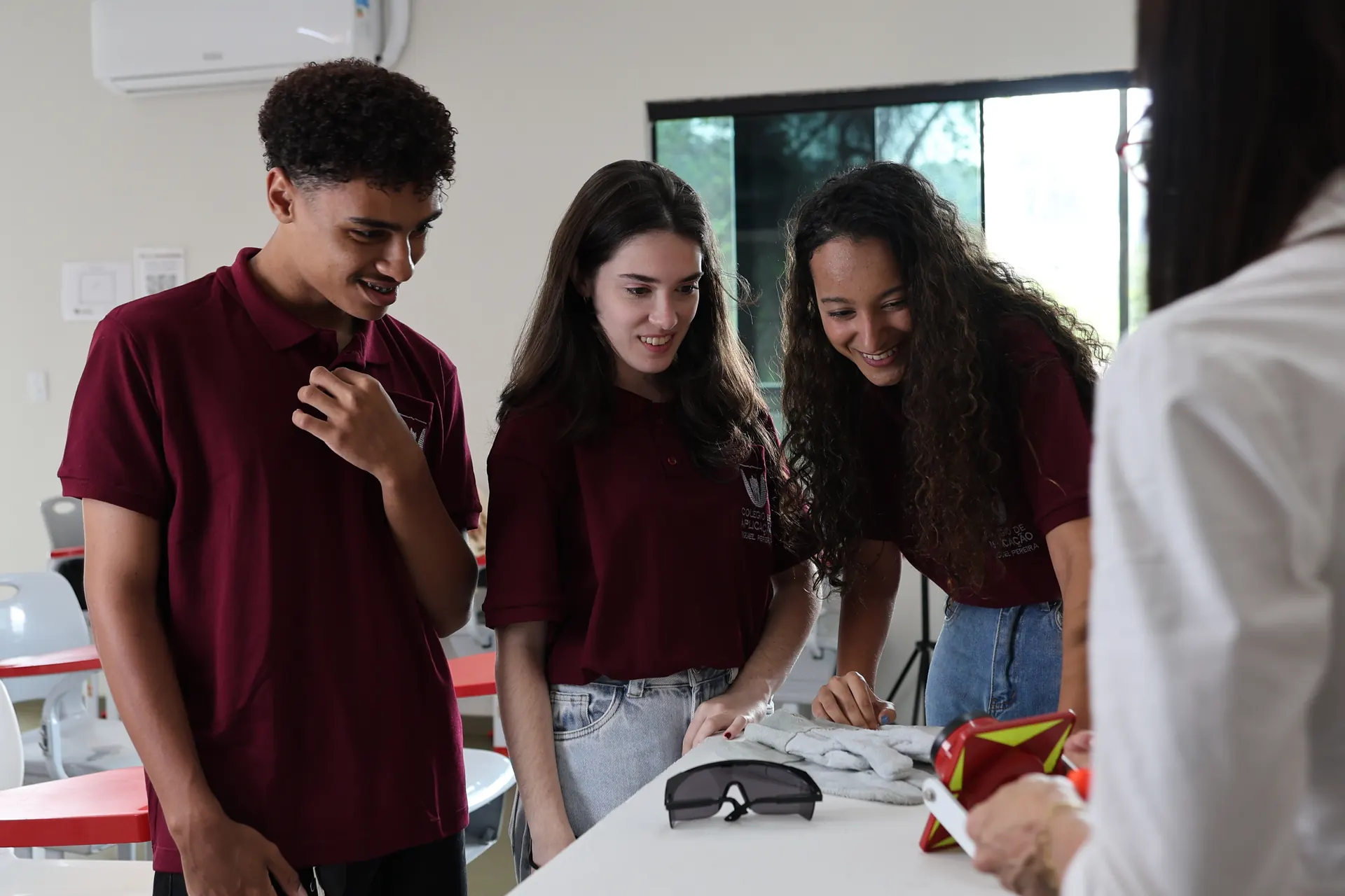 Alunos do Colégio de Aplicação Miguel Pereira, de uniforme, sorriem durante uma aula prática no laboratório